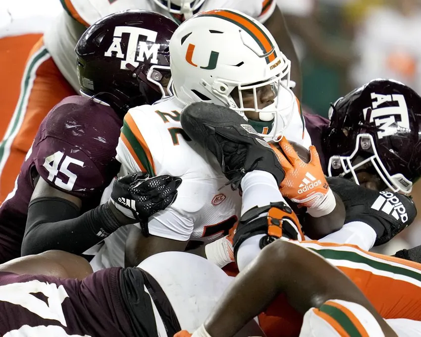 Le running back de Miami, Thaddius Franklin Jr. (22) est arrêté pour une perte de 1 yard par les défenseurs de Texas A&M, dont le linebacker Edgerrin Cooper (45), pendant la seconde moitié d'un match de football universitaire NCAA, samedi 17 septembre 2022, à College Station, Texas.