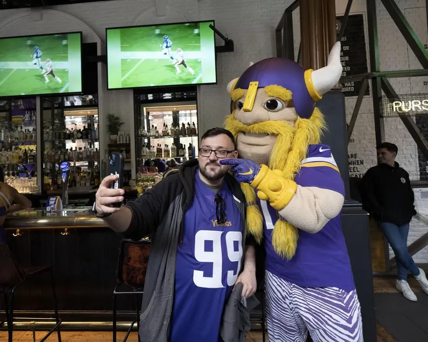 Viktor la mascotte de l'équipe des Minnesota Vikings pose pour des photos avec un supporter de l'équipe lors d'un événement d'interaction avec les fans au bar sportif The Brotherhood Of Pursuits And Pastimes à Manchester, Angleterre, mercredi 28 septembre 2022. Une demi-douzaine d'équipes de la NFL ciblent agressivement les fans en Grande-Bretagne maintenant qu'elles ont de nouveaux droits de marketing dans le pays. Elles signent des accords commerciaux et engagent des personnalités des médias locaux dans le but d'élargir leur base de fans et d'exploiter les revenus internationaux.