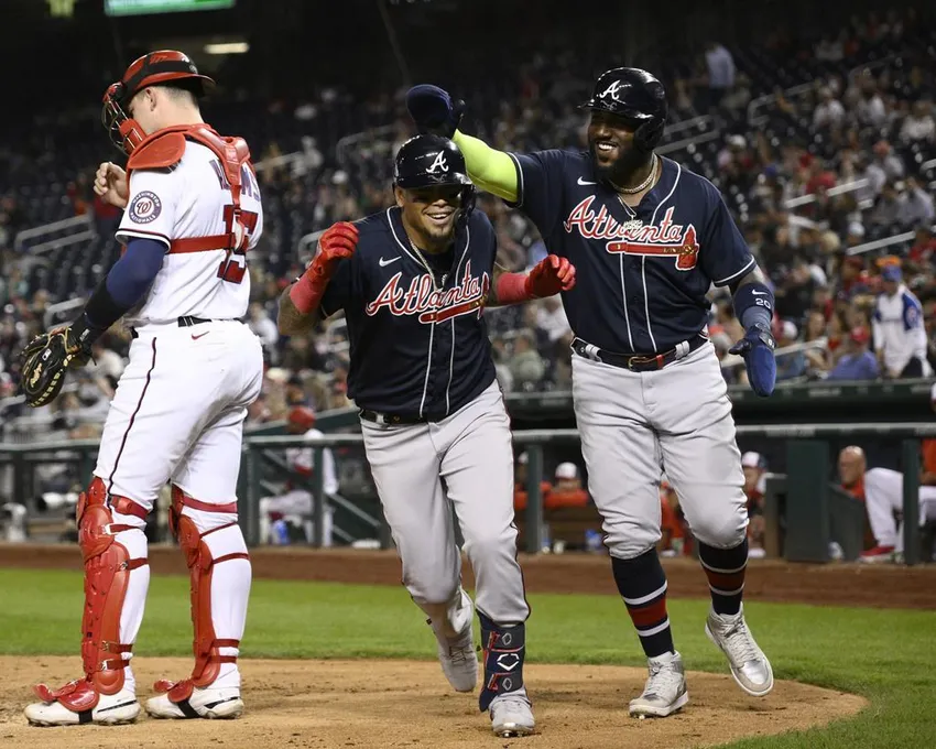 Orlando Arcia, des Braves d'Atlanta, au centre, célèbre après son home run à deux points avec Marcell Ozuna, à droite, pendant la sixième manche d'un match de baseball contre les Nationals de Washington, lundi 26 septembre 2022, à Washington. Le receveur des Nationals, Riley Adams, à gauche, ,regarde.