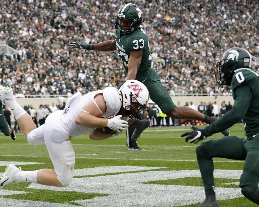 L'ailier rapproché du Minnesota Nick Kallerup, à gauche, attrape une passe pour un touchdown contre Kendell Brooks (33) et Charles Brantley, à droite, de Michigan State, pendant la deuxième mi-temps d'un match de football universitaire NCAA, samedi 24 septembre 2022, à East Lansing, Michigan. Le Minnesota a gagné 34-7.