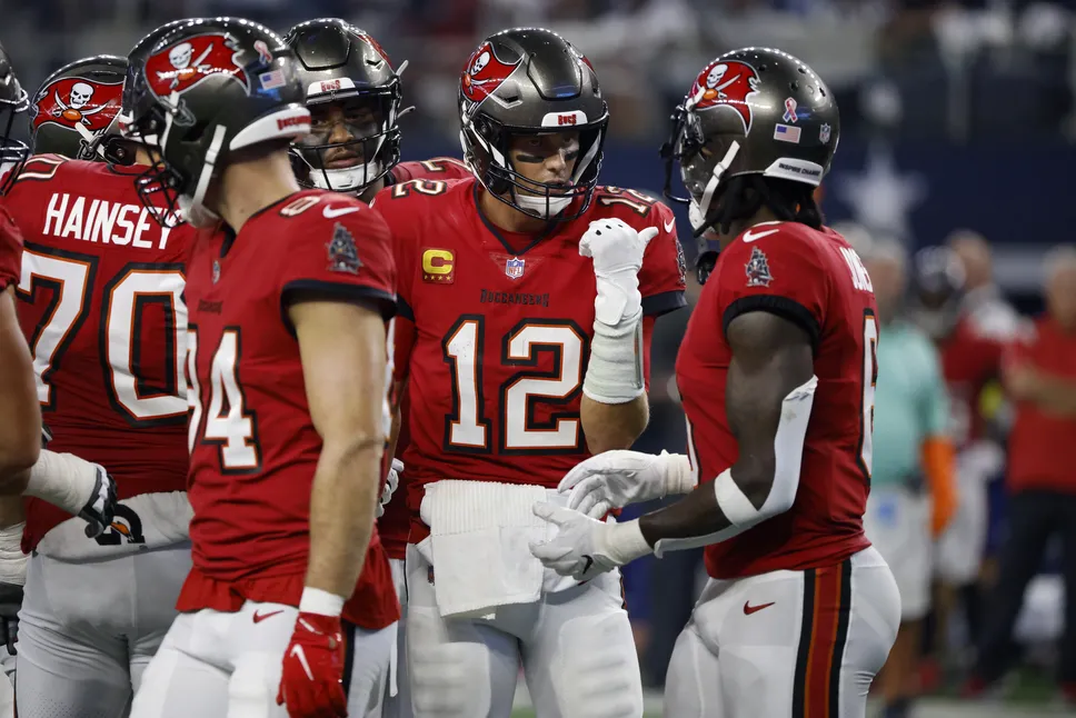 Le quarterback Tom Brady (12) des Tampa Bay Buccaneers discute avec le wide receiver Julio Jones, à droite, dans le caucus lors de la première mi-temps d'un match de football NFL contre les Dallas Cowboys à Arlington, Texas, dimanche 11 septembre 2022. (AP Photo/Ron Jenkins)