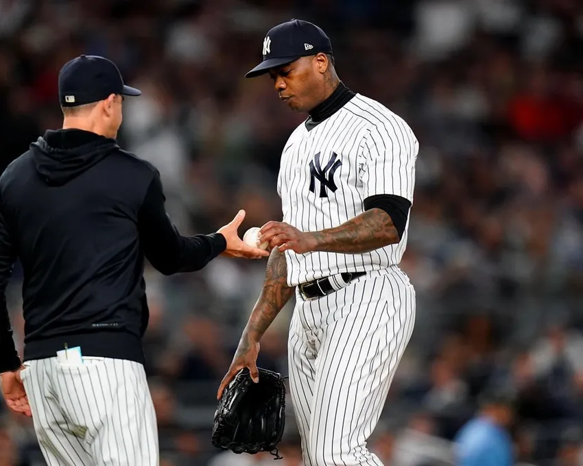 Le lanceur de relève des New York Yankees, Aroldis Chapman, remet la balle au manager Aaron Boone pendant la huitième manche d'un match de baseball contre les Boston Red Sox, le jeudi 22 septembre 2022, à New York.